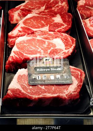 Una borsa termica con bistecche di ribeye tagliate al momento in vendita in una moderna macelleria. Foto Stock