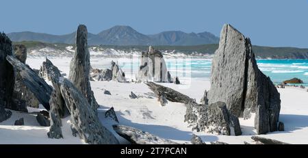 Pile di roccia e rocce erose sulla spiaggia sabbiosa con la catena montuosa del Mount Barren a Point Charles Bay, Fitzgerald River National Park, Australia Occidentale, Australia Foto Stock