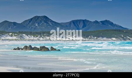 Pile di roccia e rocce erose sulla spiaggia sabbiosa con la catena montuosa del Mount Barren a Point Charles Bay, Fitzgerald River National Park, Australia Occidentale, Australia Foto Stock