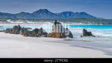 Pile di roccia e rocce erose sulla spiaggia sabbiosa con la catena montuosa del Mount Barren a Point Charles Bay, Fitzgerald River National Park, Australia Occidentale, Australia Foto Stock