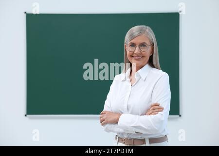 Ritratto di professore felice vicino alla lavagna in classe, spazio per il testo Foto Stock