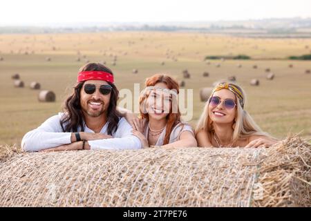 Amici hippie felici vicino alla balla di fieno nel campo Foto Stock