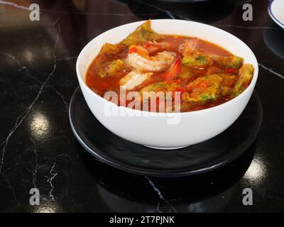 Uovo fritto con foglie di cha om o omelette di acacia e gamberi freschi in una zuppa di curry acida in una ciotola bianca, cucina asiatica tradizionale in Thailandia Foto Stock