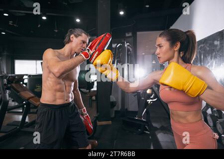 forti donne allenamento imparare kickboxing con atleta trainer in palestra fitness per muscoli e sani Foto Stock