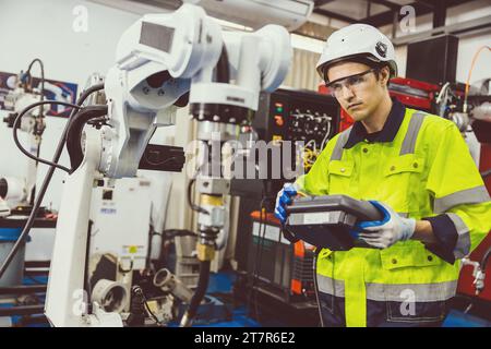 Uomo ingegnere moderno intelligente che utilizza la moderna tecnologia robotica. Configurazione del braccio di saldatura robotizzato nel processo di produzione dell'automazione in fabbrica Foto Stock