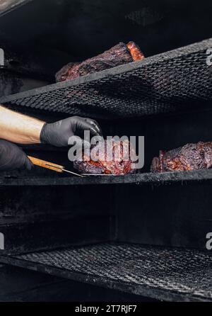 Grande grigliata per affumicatori. Carne preparata in un affumicatore per barbecue. Foto Stock