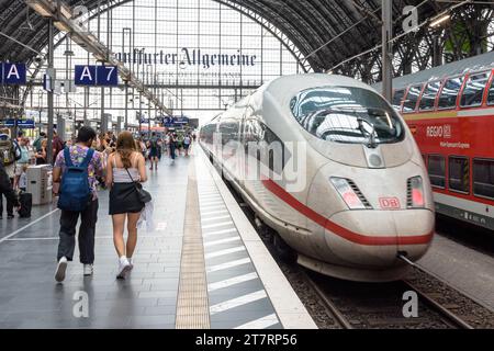 Una giovane coppia cammina sul binario della stazione centrale di Francoforte, in Germania, mentre parte un treno ad alta velocità ICE. Foto Stock