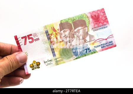 La Rupia indonesiana IDR è la valuta ufficiale dell'Indonesia. Mano di un uomo asiatico che tiene un pezzo di denaro per pagare. Business Income Investment Eco Foto Stock