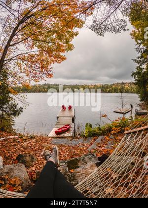 Vista del lago in autunno da una persona seduta su un'amaca. Foto Stock