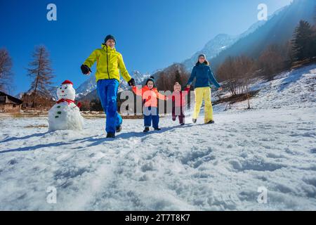 Gioiosa gestione familiare in un campo di montagna innevato sopra le soleggiate montagne Foto Stock