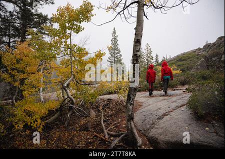 Due bambini in trekking rosso in autunno con foglie gialle Foto Stock