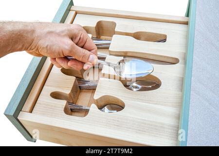 Man Hand mette il cucchiaio in un supporto in legno affettato in un primo piano del cassetto dell'armadio da cucina. La persona prende le posate dal vassoio Mobili per la casa Foto Stock