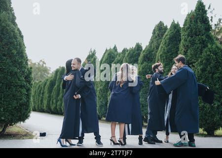 Memorabile Graduation Day con studenti universitari multietnici che celebrano il successo e i ricordi positivi a Sunny Park Foto Stock