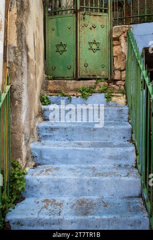 Una scala blu chiaro conduce ad un cancello con porte verdi e stelle ebraiche in un vicolo della città israeliana di Safed. Foto Stock