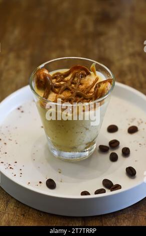 Dolce tiramisù in una tazza su un tavolo di legno Foto Stock