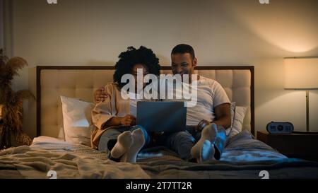 Spensierato appuntamento romantico felice famiglia rilassata coppia di coniugi afroamericani che usa il computer portatile donna che fa shopping guarda i biglietti per la consegna dei film con Foto Stock