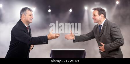 Uomini in tuta che stringono la mano sul palco Foto Stock