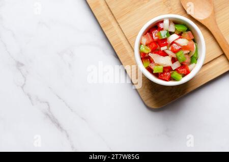 Salsa criolla argentina in una ciotola su una tavola di legno e fondo di marmo bianco con spazio per le copie. Vista dall'alto. Foto Stock