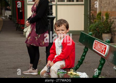 Una scena che riscalda il cuore si svolge nei panni di un bambino di 6 anni e di sua madre single, in attesa pazienza dell'arrivo del treno Foto Stock