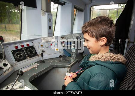 Un ragazzo eccitato finalmente può sedersi su un treno diesel, con gli occhi spalancati e meravigliati davanti alla gamma di comandi. Foto Stock