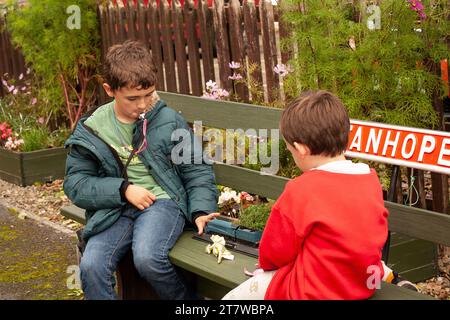 Anticipazione della Heritage Railway: Due giovani fratelli di 6 e 12 anni attendono con ansia il loro treno a Stanhope, contea di Durham. Impegnato nel gioco Foto Stock