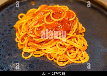 Spaghetti con salsa di pomodoro da vicino su piatto nero Foto Stock