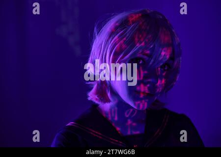 ritratto di donna in parrucca bionda con proiezione di geroglifici su luce al neon blu, concept anime Foto Stock