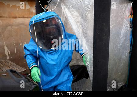 La persona indossa i dispositivi di protezione individuale (DPI) blu con maschera antigas per la protezione dall'inquinamento atmosferico e dai rischi biologici. Foto Stock