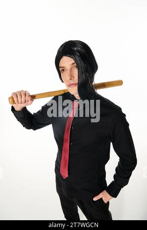 uomo sicuro di sé con parrucca nera e cravatta rossa che tiene in mano la mazza da baseball e che guarda lontano dal bianco, stile anime Foto Stock