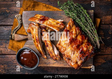 Costolette di maiale alla griglia Baby Back su un asse di legno. Sfondo di legno. Vista dall'alto. Foto Stock