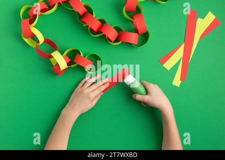 le mani delle ragazze fanno catena di carta per la decorazione di natale di capodanno dyi occupazione facile a casa Foto Stock