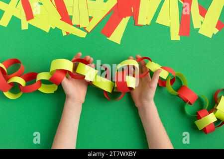 le mani delle ragazze fanno catena di carta per la decorazione di natale di capodanno dyi occupazione facile a casa Foto Stock
