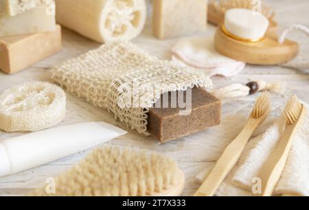 Sapone beige organico fatto a mano in un sacchetto salvasapone vicino a articoli igienici - spugne naturali, spazzolini da denti di bambù e tamponi di cotone da vicino. Erbe naturali Foto Stock