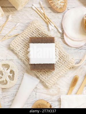 Sapone beige organico fatto a mano con etichetta vuota sul sacchetto salvapezzo vicino a articoli igienici - spugne e spazzolino naturali, spazzolini in bambù e bastoncino di cotone Foto Stock