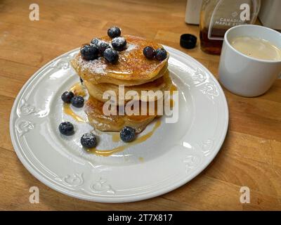 Una pila di pancake ai mirtilli appena fatti con sciroppo d'acero e caffè. Foto Stock