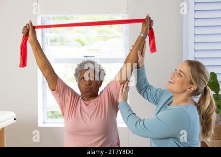 Fisioterapista femminile caucasica e paziente afrcia americana anziana con banda, spazio copia Foto Stock