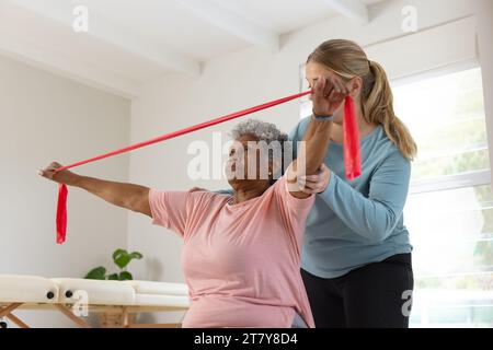 Fisioterapista femminile caucasica e paziente afrcia americana anziana con banda, spazio copia Foto Stock