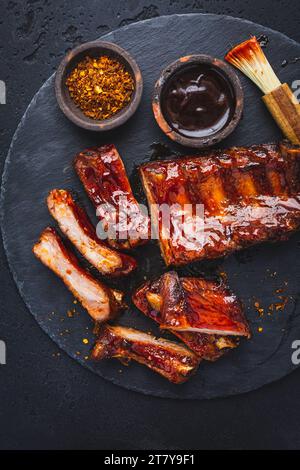 Costolette di maiale al barbecue con marinata di peperoncino al miele caldo su nero Foto Stock