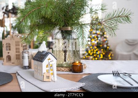 Casa minuscola e chiave di piccole dimensioni in una casa intima con decorazioni natalizie sul tavolo della cucina festosa. Regalo per Capodanno. Assicurazione, trasferirsi in una nuova casa, m Foto Stock