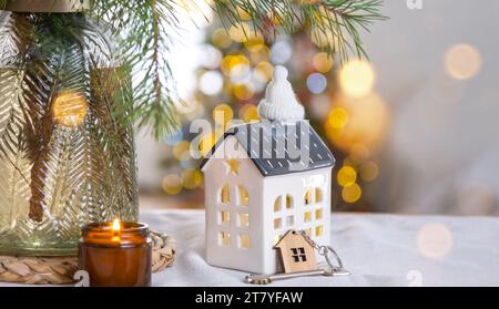 Casa minuscola e chiave di piccole dimensioni in una casa intima con decorazioni natalizie sul tavolo della cucina festosa. Regalo per Capodanno. Assicurazione, trasferirsi in una nuova casa, m Foto Stock