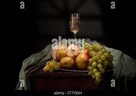 Natura morta con frutta e vino in stile retrò frutta succosa sdraiata sul tavolo. Natura morta di pere, uva e vino. Foto Stock