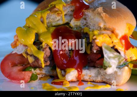 Vista frontale di un hamburger vegetariano morso in un panino con ketchup su una piastra bianca isolata su uno sfondo bianco. . Foto di alta qualità Foto Stock