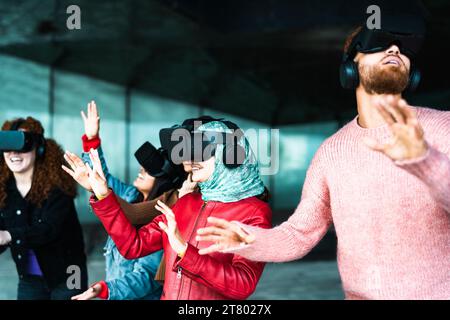 Giovani amici multirazziali che utilizzano occhiali futuristici per realtà virtuale - tecnologia e concetto metavense Foto Stock