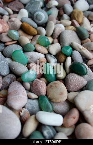 Le pietre di quarzo verde sono sparse su piccoli ciottoli con conchiglie verticali per gli sfondi Foto Stock