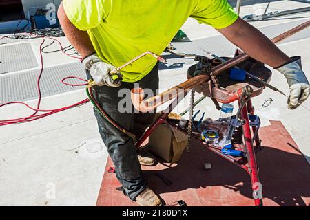 Operaio edile che si prepara a brasare un gomito su una lunghezza di tubo di rame sul tetto in un magazzino di stoccaggio a freddo a CO2 (refrigerazione industriale) Foto Stock