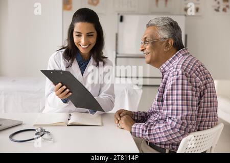 Allegro medico donna che mostra rapporto medico a uomo paziente anziano Foto Stock