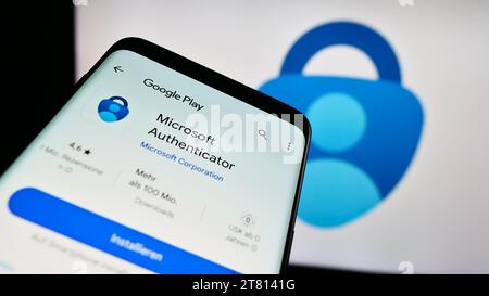 Telefono cellulare con sito Web dell'app di autenticazione Microsoft Authenticator davanti al logo dell'azienda. Mettere a fuoco in alto a sinistra sul display del telefono. Foto Stock