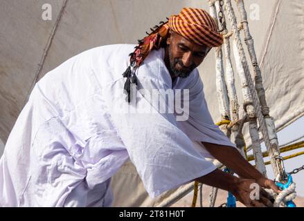 Vestito con abiti tradizionali, un barcaiolo del Nilo mans a Felucca, la barca tradizionale ancora presente sul Nilo Foto Stock