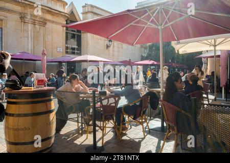 Persone sedute sulla terrazza di un bar con sedie, tavoli e ombrelloni nella piazza Pescadería del mercato centrale della città di Castellon Foto Stock