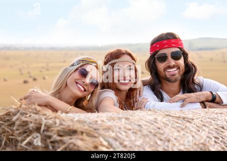 Amici hippie felici vicino alla balla di fieno nel campo Foto Stock